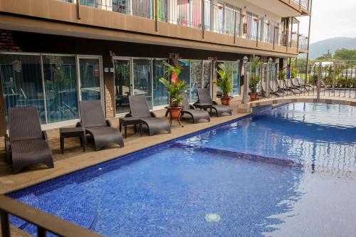 a hotel swimming pool with chairs and a building at Beachfront Hotel Tramonto in Jacó
