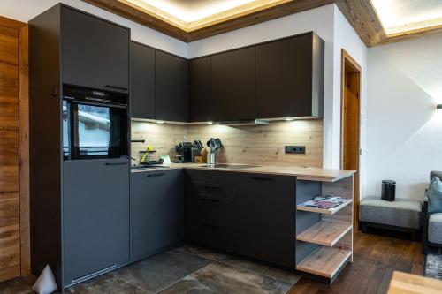 a kitchen with black cabinets and a sink at Big Seven Ferienwohnungen Seiwald in Fieberbrunn