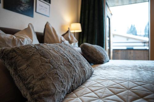 a bedroom with a bed with pillows and a window at Big Seven Ferienwohnungen Seiwald in Fieberbrunn