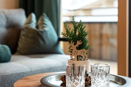 a table with a christmas tree and two glasses at Big Seven Ferienwohnungen Seiwald in Fieberbrunn