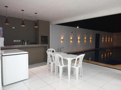 eine Küche mit einem weißen Tisch und weißen Stühlen in der Unterkunft Casa com Piscina, hidromassagem e churrasqueira. in Canoa Quebrada