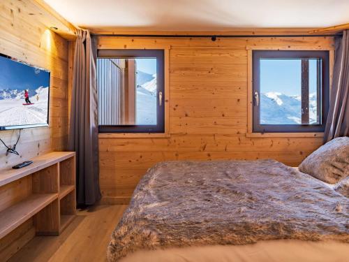 Un dormitorio con una cama y un televisor y ventanas. en Appartement montagne rénové, 6 pers, proche pistes et commodités - FR-1-637-59, en Val Thorens