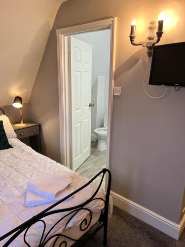 a bedroom with a bed and a bathroom with a toilet at White horse in Empingham