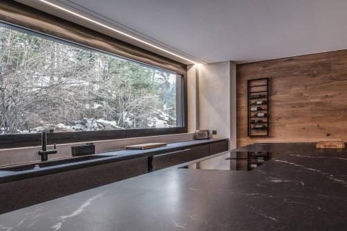 a kitchen with a sink and a large window at Black Summit Boutique Resort Laax in Laax