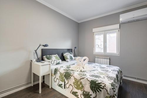 a bedroom with a bed with a white and green blanket at Apartamento Palacio Aranjuez Completo 2H - Warner Park Near in Aranjuez