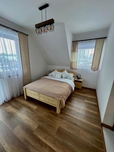 a bedroom with a bed and two windows at Rozeta in Witów