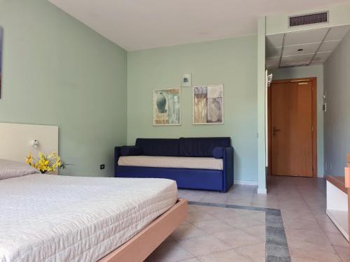 a bedroom with a bed and a blue couch at Hotel La Buca Del Gatto in Marina di Cecina