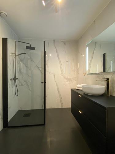 a bathroom with a glass shower and a sink at Unique Apartments Tromsø in Tromsø