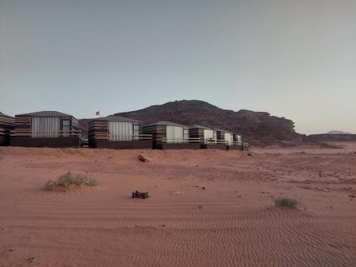 una fila de edificios en un desierto con una montaña en Hakuna matata desert camp, en Wadi Rum