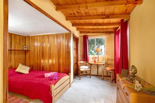 1 dormitorio con cama roja y mesa en Welcome in Paradise en La Matanza de Acentejo