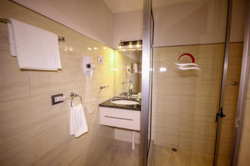 a bathroom with a shower and a sink and a phone at Beachfront Hotel Tramonto in Jacó