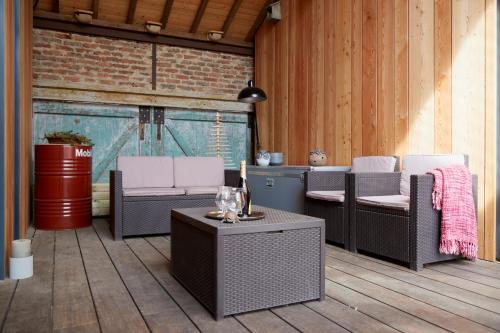 a patio with wicker chairs and a table at Superbe grange réaménagée in Fampoux