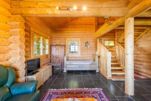 a living room with a couch and a television in a log cabin at AlpenRose - 8 pers - avec cachet -pres des pistes in Plan Fey