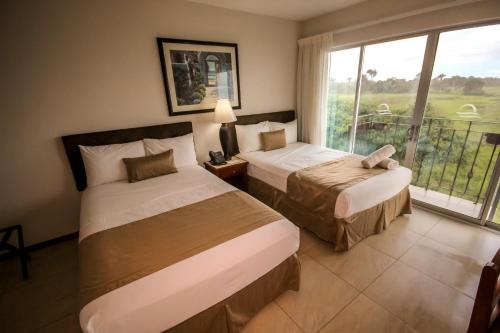 two beds in a hotel room with a window at Beachfront Hotel Tramonto in Jacó