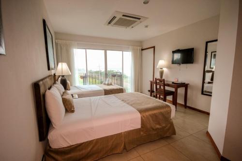 a hotel room with two beds and a window at Beachfront Hotel Tramonto in Jacó