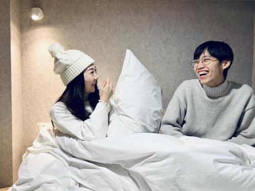 a man and a woman sitting in bed talking at Sasa Youth Hostel in Jiaoxi