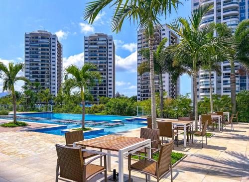 un patio con mesas y sillas junto a una piscina en Apto c vista p o mar e lagoa na Barra da Tijuca RJ en Río de Janeiro