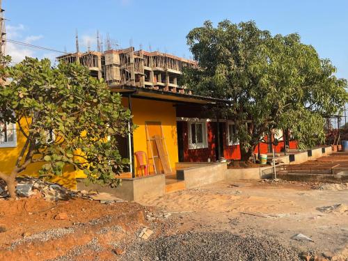 uma casa amarela com uma árvore em frente em Hemprabha Bed & Breakfast, Ratnagiri em Ratnagiri
