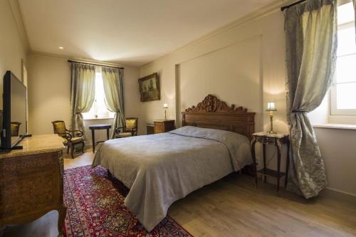 een slaapkamer met een bed, een stoel en een raam bij Chambres d'hôtes de Château Renon in Tabanac