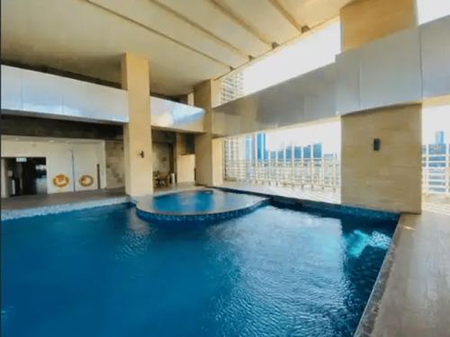 a large swimming pool with blue water in a building at Luxury Apartement Rasuna Jakarta by Lentera in Jakarta