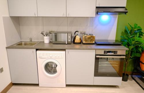 a kitchen with a washing machine and a sink at GoldersGreen Apartments by Sleepy in London