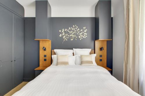 une chambre avec un grand lit avec des draps blancs dans l'établissement Séjours Parisiens / Suite Belle Courcelles / 4*, à Paris