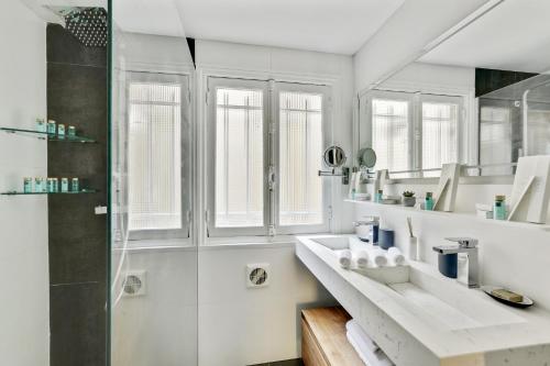 une salle de bain blanche avec un lavabo et une douche dans l'établissement Séjours Parisiens / Suite Belle Courcelles / 4*, à Paris