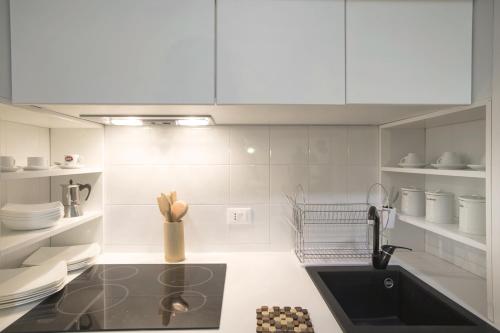 eine Küche mit weißen Schränken und einem schwarzen Waschbecken in der Unterkunft Appartamento-Studio con cortile in Trapani