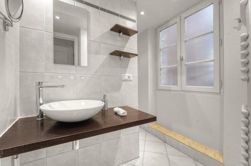une salle de bain blanche avec un lavabo et un miroir dans l'établissement L'encrier - Appt confortable pour 2, à Toulouse