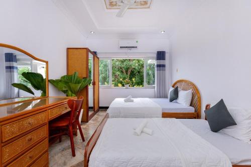 a hotel room with two beds and a desk and a mirror at A5 Ngọc Tước - Villa Hồ Bơi Gần Biển Bãi Sau - Free Bida + Karaoke in Vung Tau
