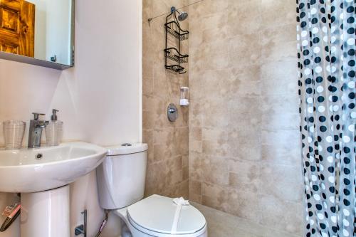 La salle de bains est pourvue de toilettes, d'un lavabo et d'une douche. dans l'établissement Muna Santa Rosa Apartamentos, à Tamarindo