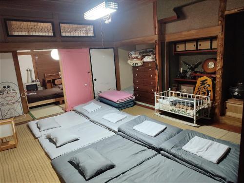 a room with three beds and a dresser at 愛犬と家族みんなでのんびり羽休めv古民家民泊OMOTENASHI LODGe 悠遊 in Nakafurano