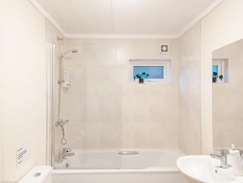 a white bathroom with a tub and a sink at Elm Lodge in Bosham