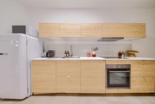 une cuisine avec des armoires en bois et un réfrigérateur blanc dans l'établissement NOCNOC - Le Zellige - Petite piscine et jardin en ville, à Montpellier