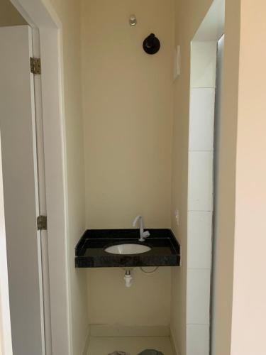 a bathroom with a sink with a black counter at Mini Casa 02 em Cabo Frio in Cabo Frio