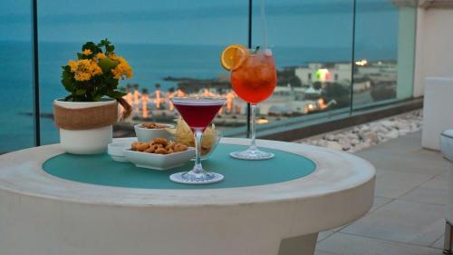 Bianco Riccio Suite Hotel في سافيلّيتري دي فاسانو: مشروبان على طاولة مطلة على المحيط