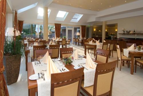 uma sala de jantar com mesas e cadeiras num restaurante em Mercator-Hotel em Gangelt