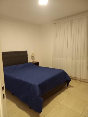 Un dormitorio con una cama azul y una ventana en LAS VICTORIAS HOME V en Río Cuarto