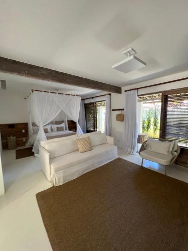 ein Wohnzimmer mit einem weißen Sofa und einem Bett in der Unterkunft Hotel Boutique Vila São João in Trancoso