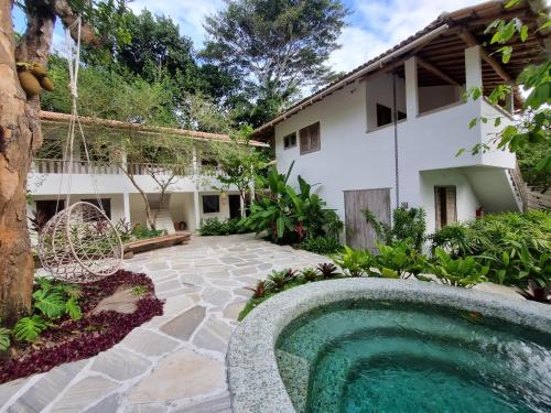 un patio trasero con piscina y una casa en Hotel Boutique Vila São João, en Trancoso
