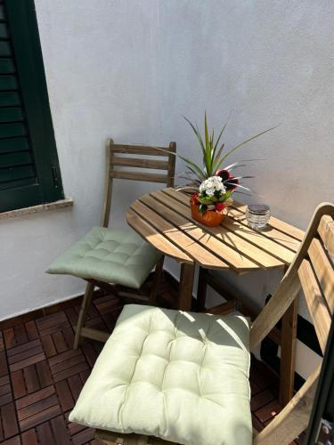 a wooden table and chairs with a plant on it at Appartamento vicino spiaggia in Portoscuso