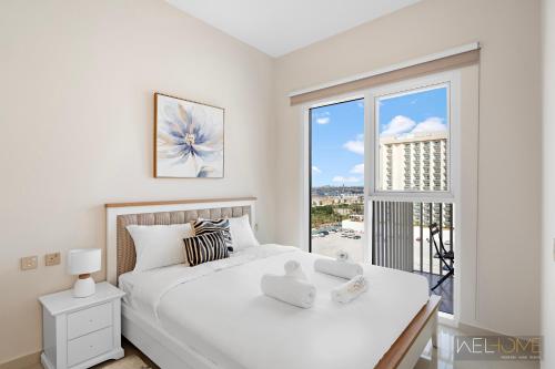 1 dormitorio con cama blanca y ventana grande en WelHome - Breathtaking View 1BR Apt in Damac Hills 2 en Dubái