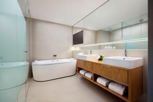 La salle de bains est pourvue de 2 lavabos, d'une baignoire et d'un miroir. dans l'établissement Four Points by Sheraton Sydney, Central Park, à Sydney