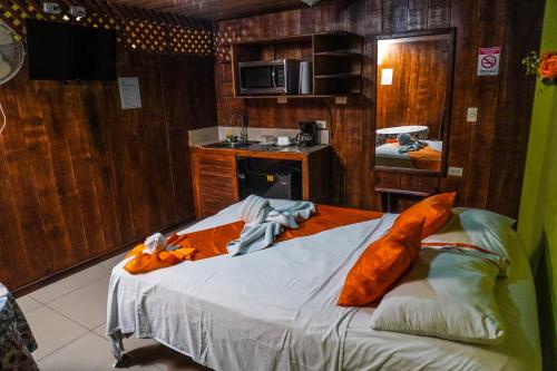 a bedroom with a large bed with orange sheets at Hospedaje Angeluz in Quesada