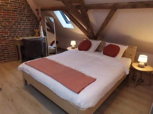 una camera da letto con un grande letto bianco con cuscini rossi di B&B Den Bruynen Bergh a Beernem