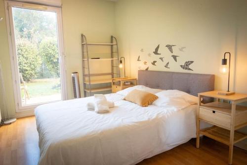 ein Schlafzimmer mit einem weißen Bett mit Vögeln an der Wand in der Unterkunft Le jardin de Christine in Saint-Martin-dʼHères