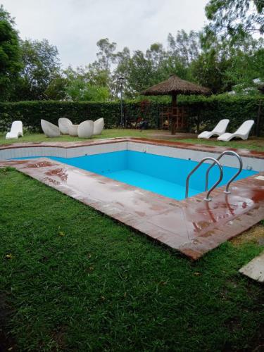 una piscina en la hierba con sillas alrededor en Daily Suites Hotel Boutique en Cañuelas