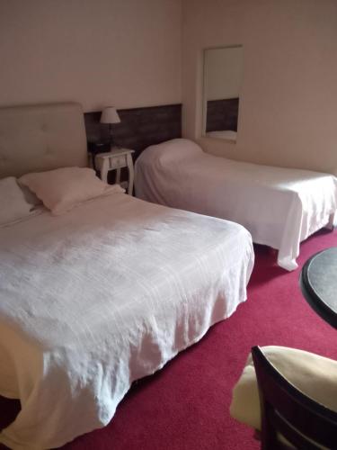 Habitación de hotel con 2 camas y mesa en Daily Suites Hotel Boutique en Cañuelas