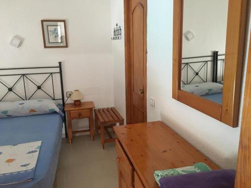 Schlafzimmer mit einem Bett, einem Spiegel und einem Tisch in der Unterkunft Roquemar dreams 613 in Roquetas de Mar