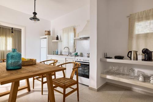 a white kitchen with a wooden table and chairs at Villa Manikas Milos in Adamas